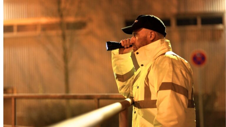 Guard says he looked up from his phone at 1 a.m. and found a shirtless stranger already inside the yard — and for the next few minutes he had to keep his gun on him while backing through scrap and tripping hazards